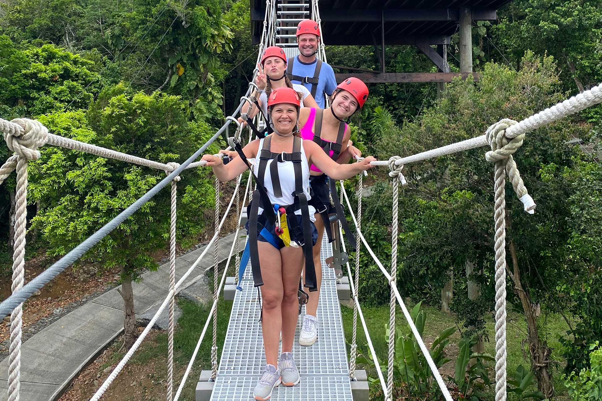 Four zipline guests smiling and laughing as they cross a suspension bridge at Tree Limin Extreme Zipline.