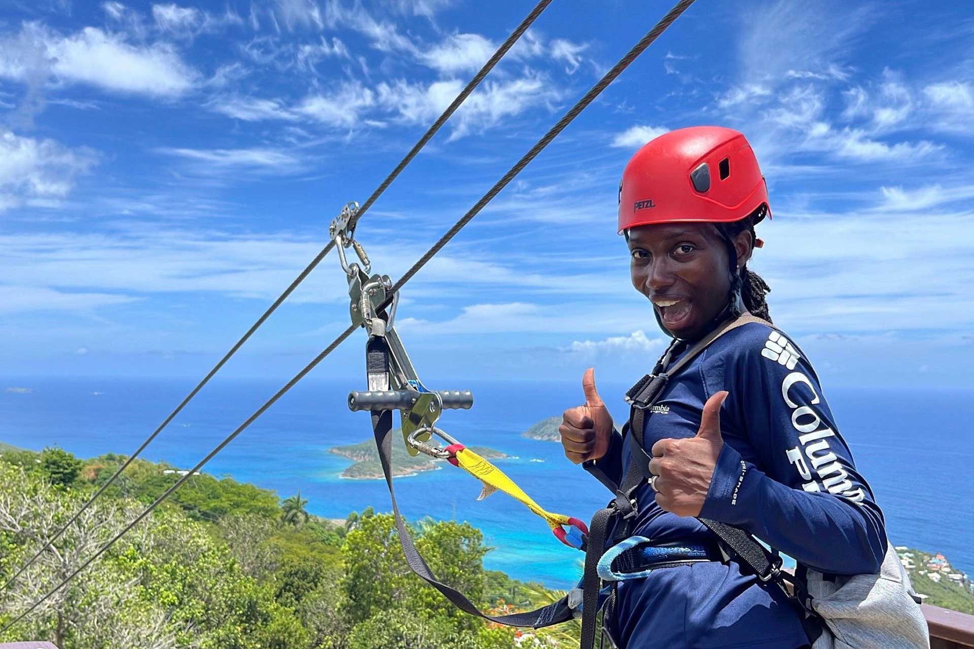Guest smiling with two thumbs up on the famous 'Yo-Yo' zip with Caribbean islands and turquoise water.
