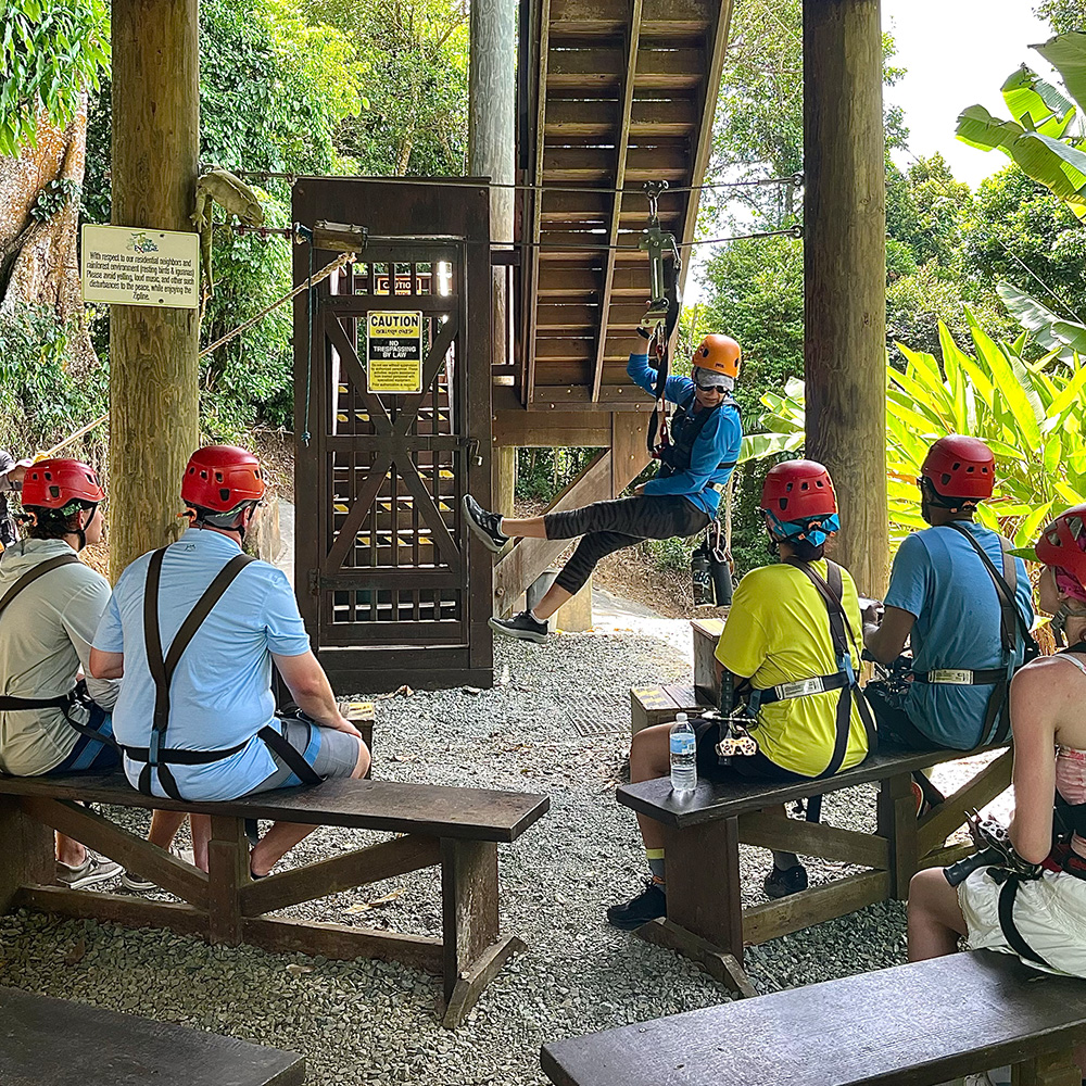 Guide demonstrating safety protocols and explaining rules of ziplining to the group.